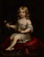 Portrait of a young boy seated on a cushion holding flowers