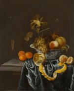 Still life of a porcelain bowl with peaches and grapes, a peeled lemon, apricot, and a façon de Venise wine glass on a partially draped stone ledge