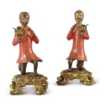 A PAIR OF QING DYNASTY GILT AND LACQUERED BRONZE ONE-LIGHT CANDELABRA IN THE FORM OF KNEELING BRONZE FIGURES OF EUROPEANS ON LOUIS XV GILT BRONZE BASES, MID-18TH CENTURY