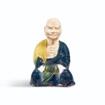 A RARE BLUE AND AMBER-GLAZED SEATED FIGURE OF A LUOHAN, TANG DYNASTY | 唐 藍釉羅漢坐像