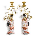 A pair of Japanese porcelain figural wall flower holders, with later porcelain flower mounted bronze branches, the Japanese porcelain 18th century, the gilt-bronze and flowers 19th century