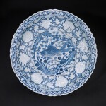 A unique and highly important moulded blue and white barbed 'fish' charger, Yuan dynasty | 元 青花魚藻凸花牡丹菱口大盤