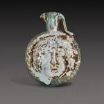 A Roman Pale Green Mould-Blown Janiform Glass Flask, circa 1st/2nd century A.D.