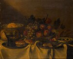 FOLLOWER OF FRANS YKENS | A still life with a fruit bowl, bread rolls, and a wine glass on a table