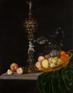 Still life with an elaborate silver gilt standing cup, a basket of fruit, and a glass wine jug upon a partly draped table